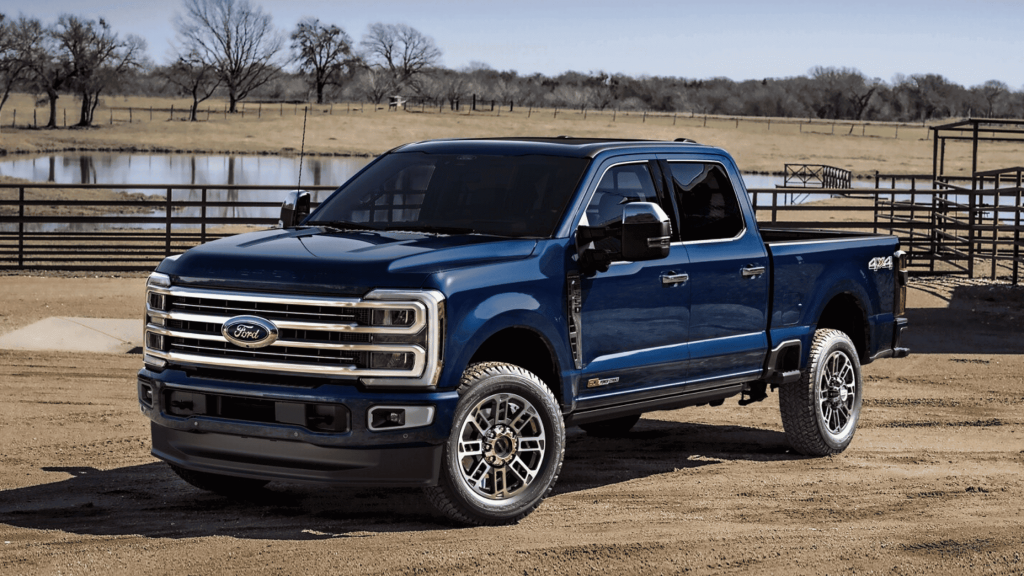 A rugged blue 2025 Ford Super Duty® F-350 parked on a dirt road near a fenced ranch. Learn how this heavy-duty truck excels in towing performance and work-ready durability in Cleveland Heights.