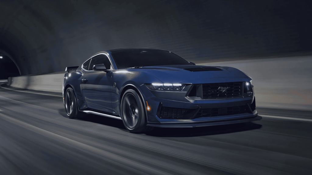 2025 Ford Mustang® sports car in deep blue, racing through a tunnel with an aggressive stance and high-performance aerodynamics.