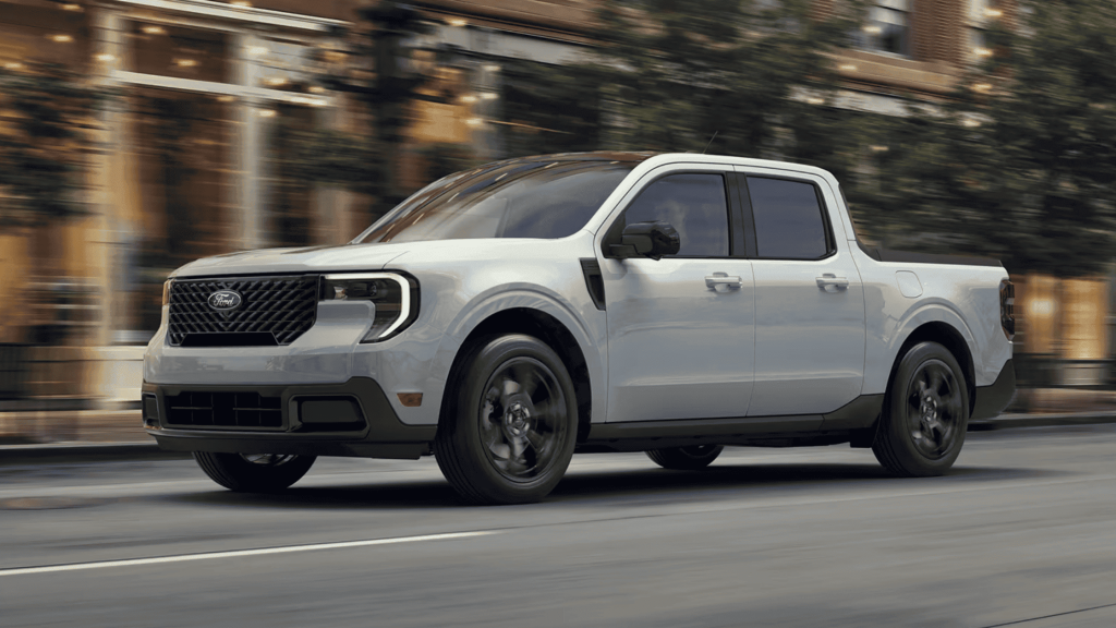 2025 Ford Maverick® compact pickup truck in motion on city streets, featuring a modern design and black alloy wheels.