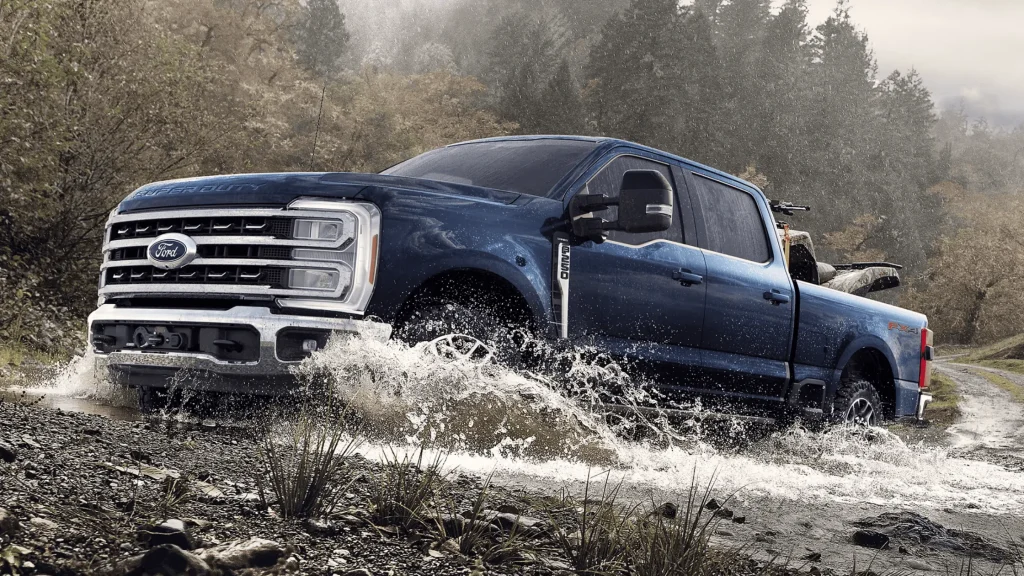 2025 Ford Super Duty F-250 driving through water and mud on a rugged trail, emphasizing its off-road and towing strength.