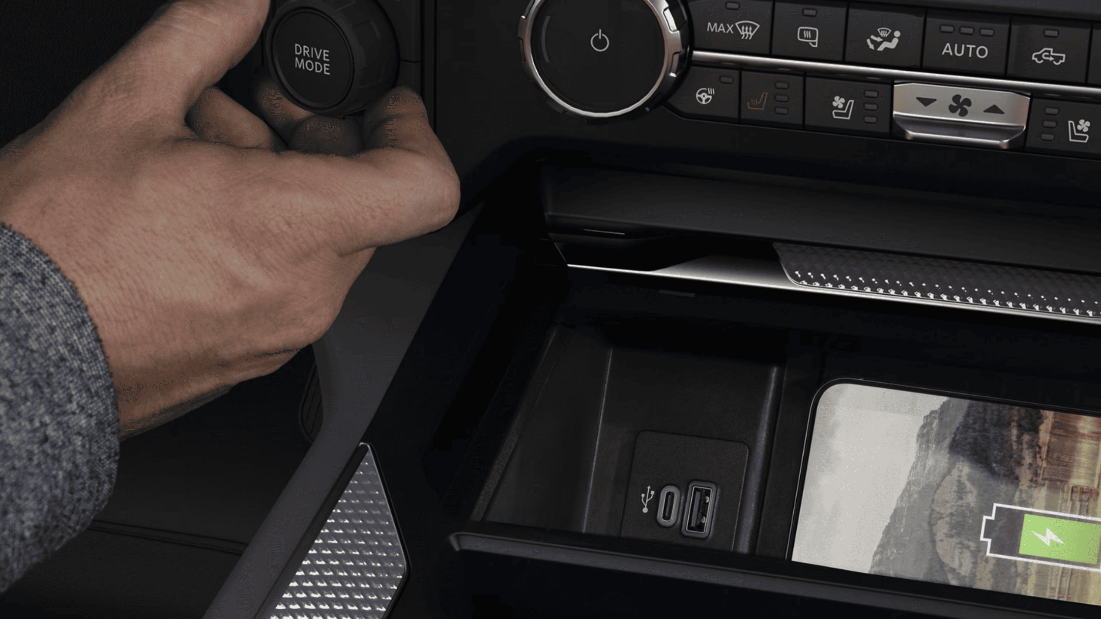 Close-up of a driver adjusting the 2025 Ford Super Duty® F-250® drive mode dial, with nearby USB ports and wireless phone charging pad visible.