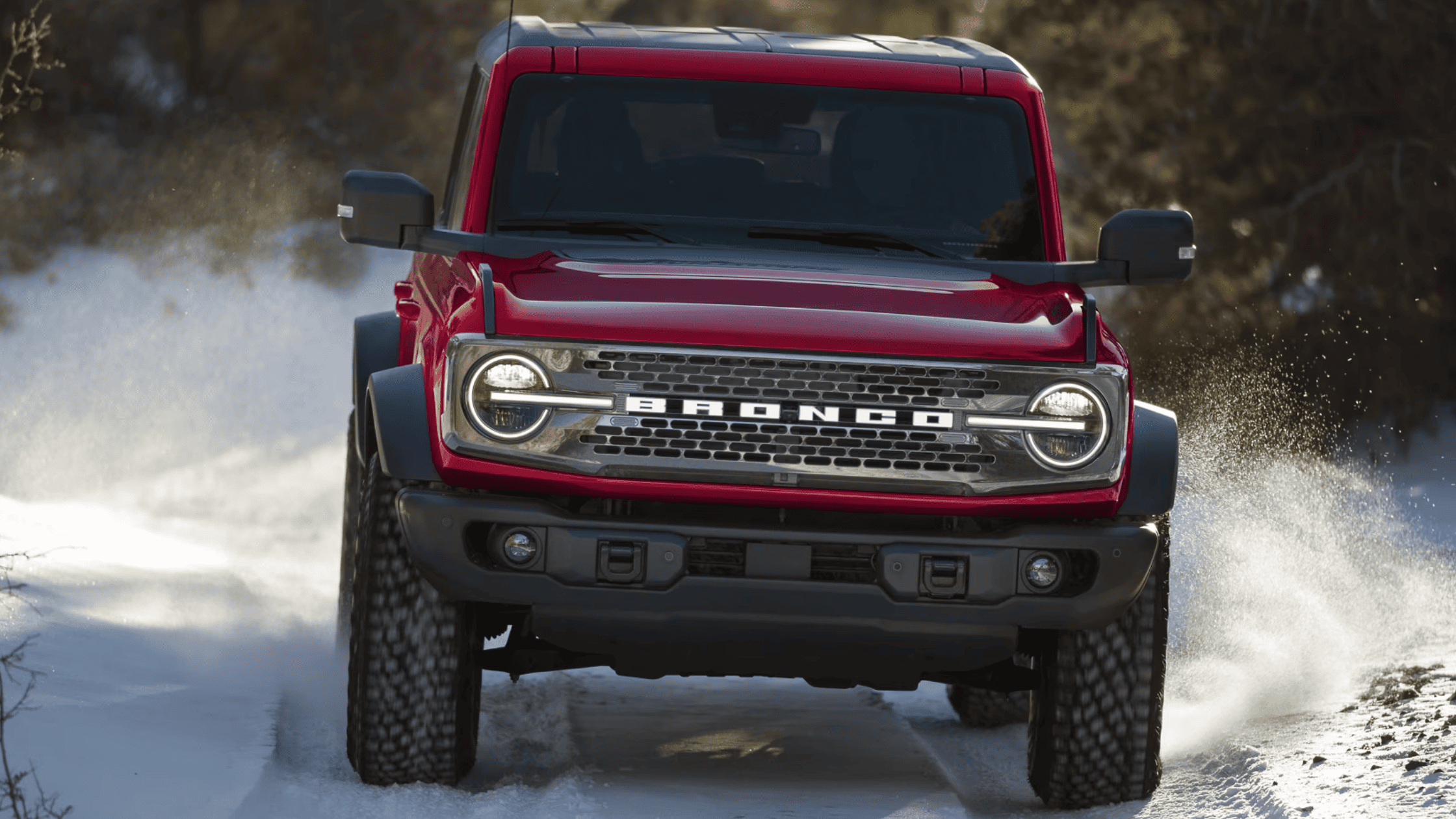 Front view of a red 2025 Ford Bronco® driving confidently through snow, highlighting off-road performance near Mentor, OH.