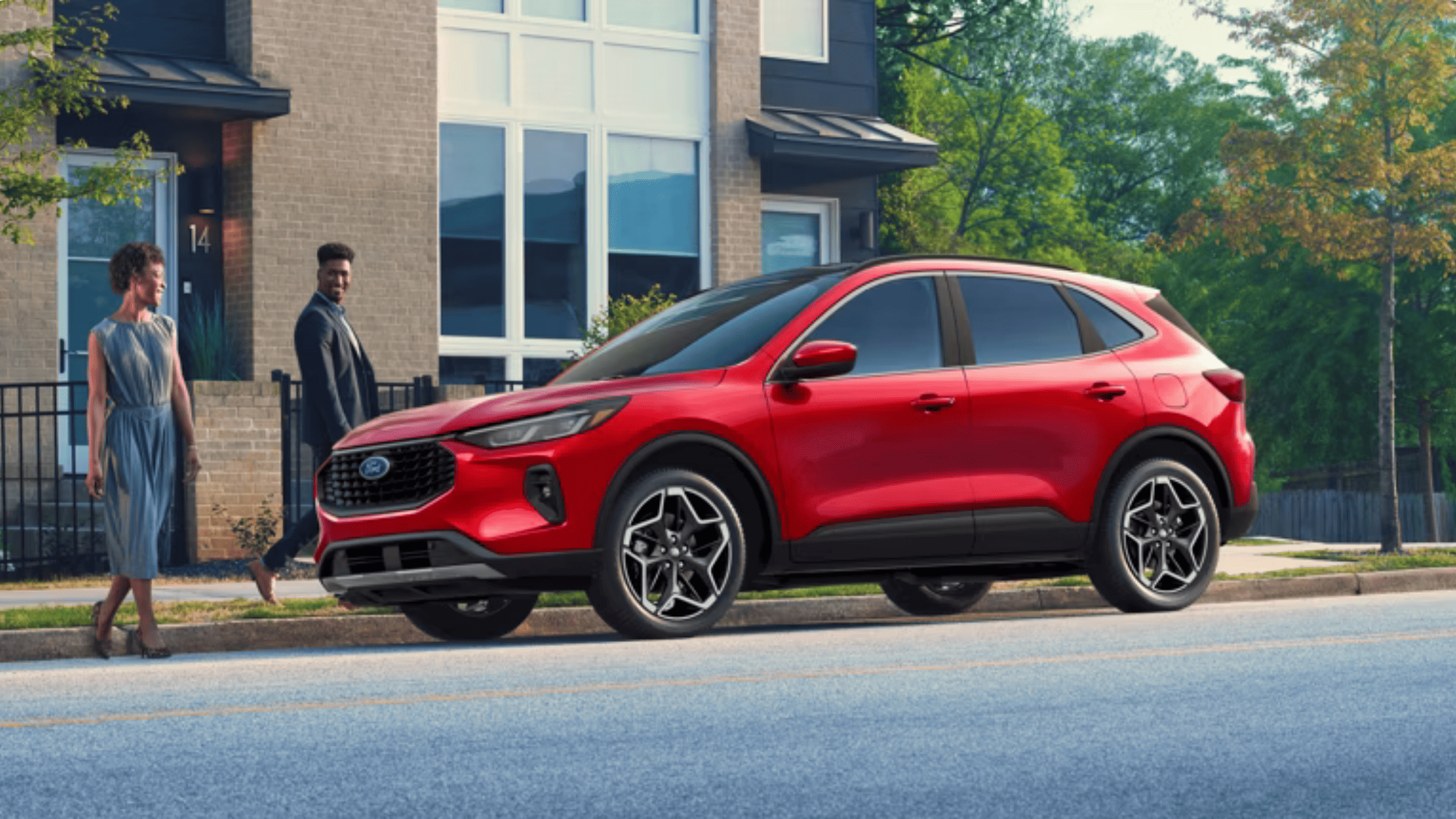 2025 Ford Escape® ST-Line Hybrid parked curbside in Concord, OH with a sleek red exterior and sporty black wheels.
