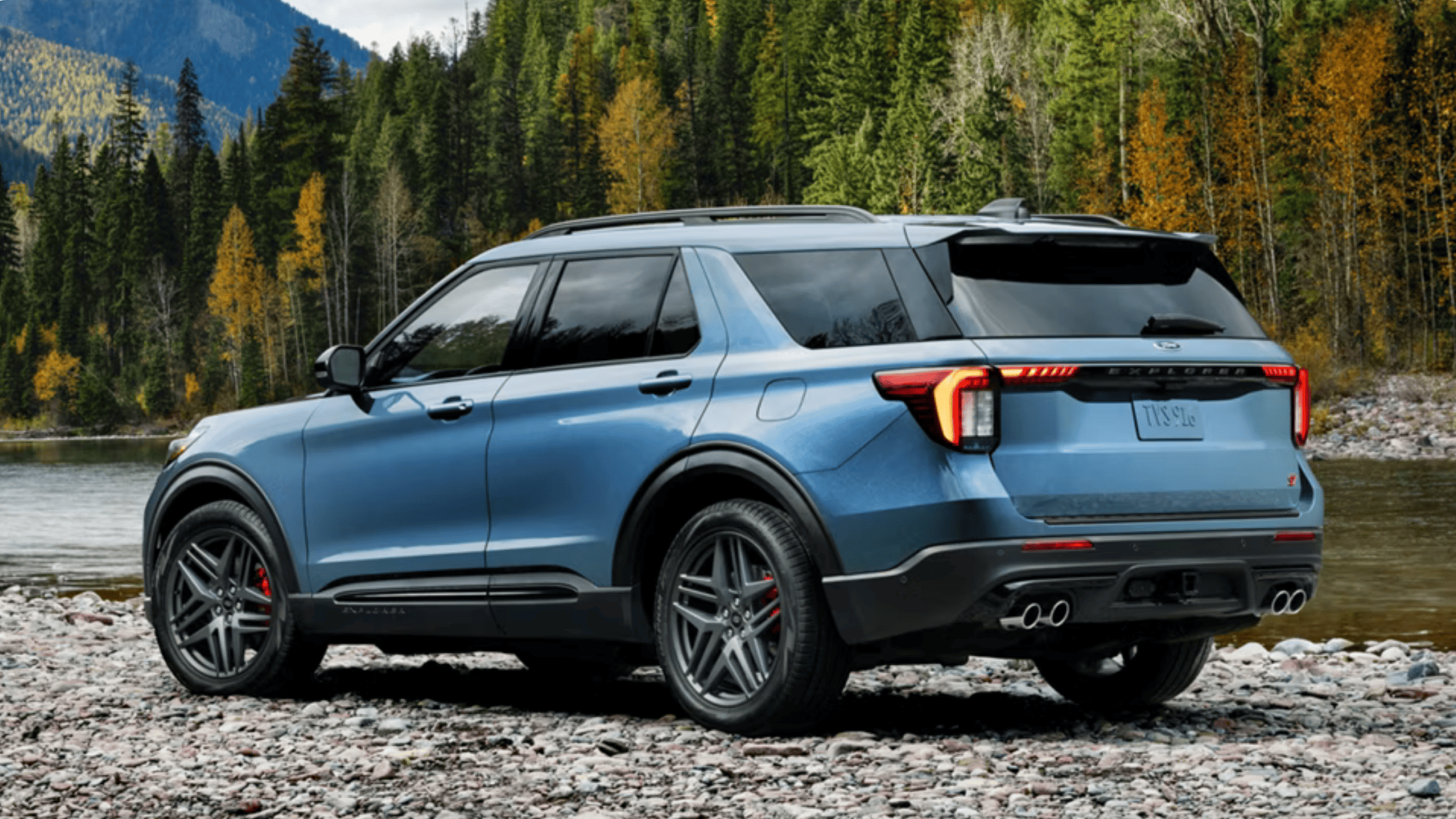 2025 Ford Explorer® in blue parked on a rocky riverside trail near Concord, OH with forested mountains in the background.