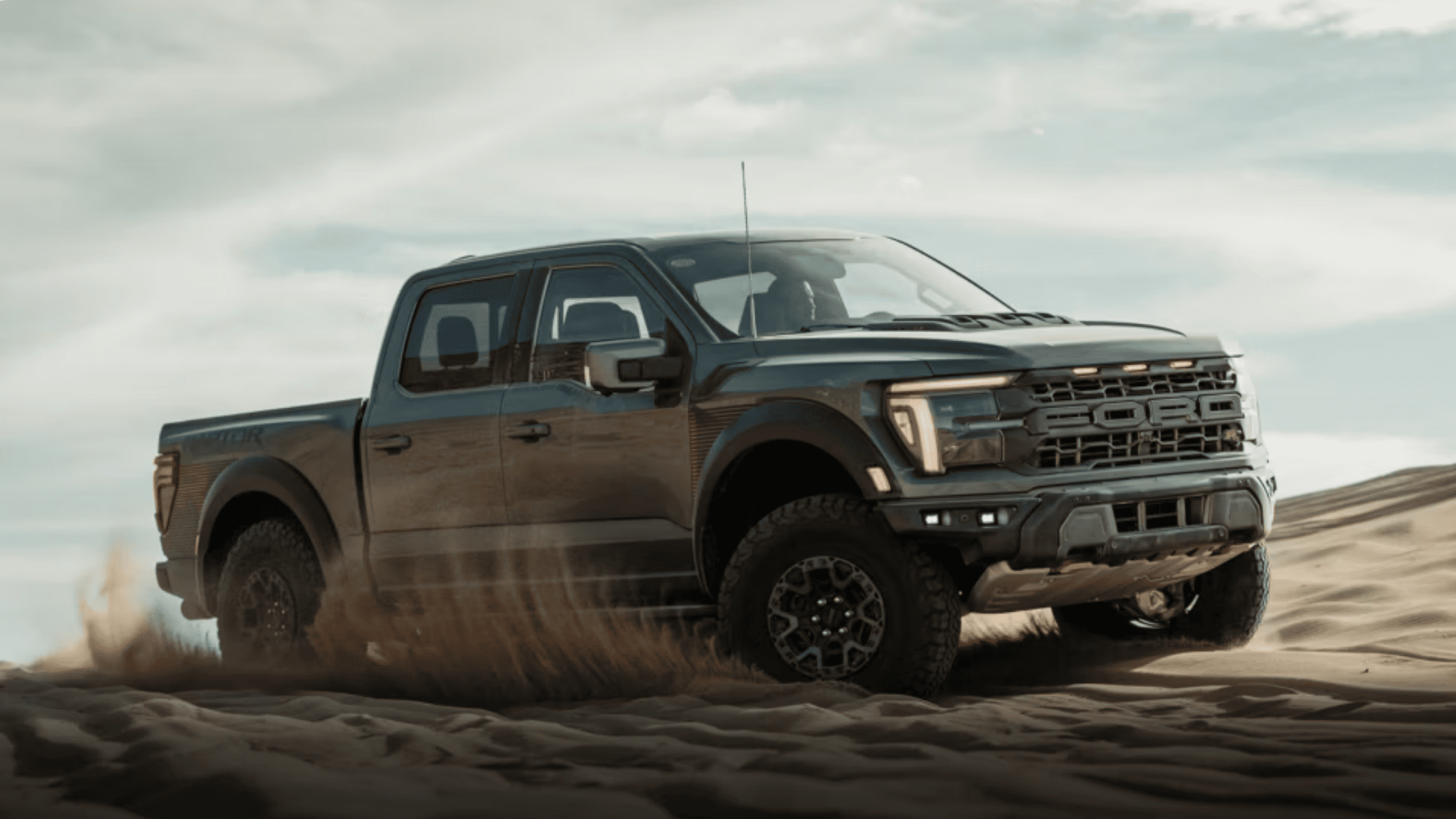 2025 Ford F-150® Raptor kicking up sand while off-roading across desert dunes near Concord, OH.