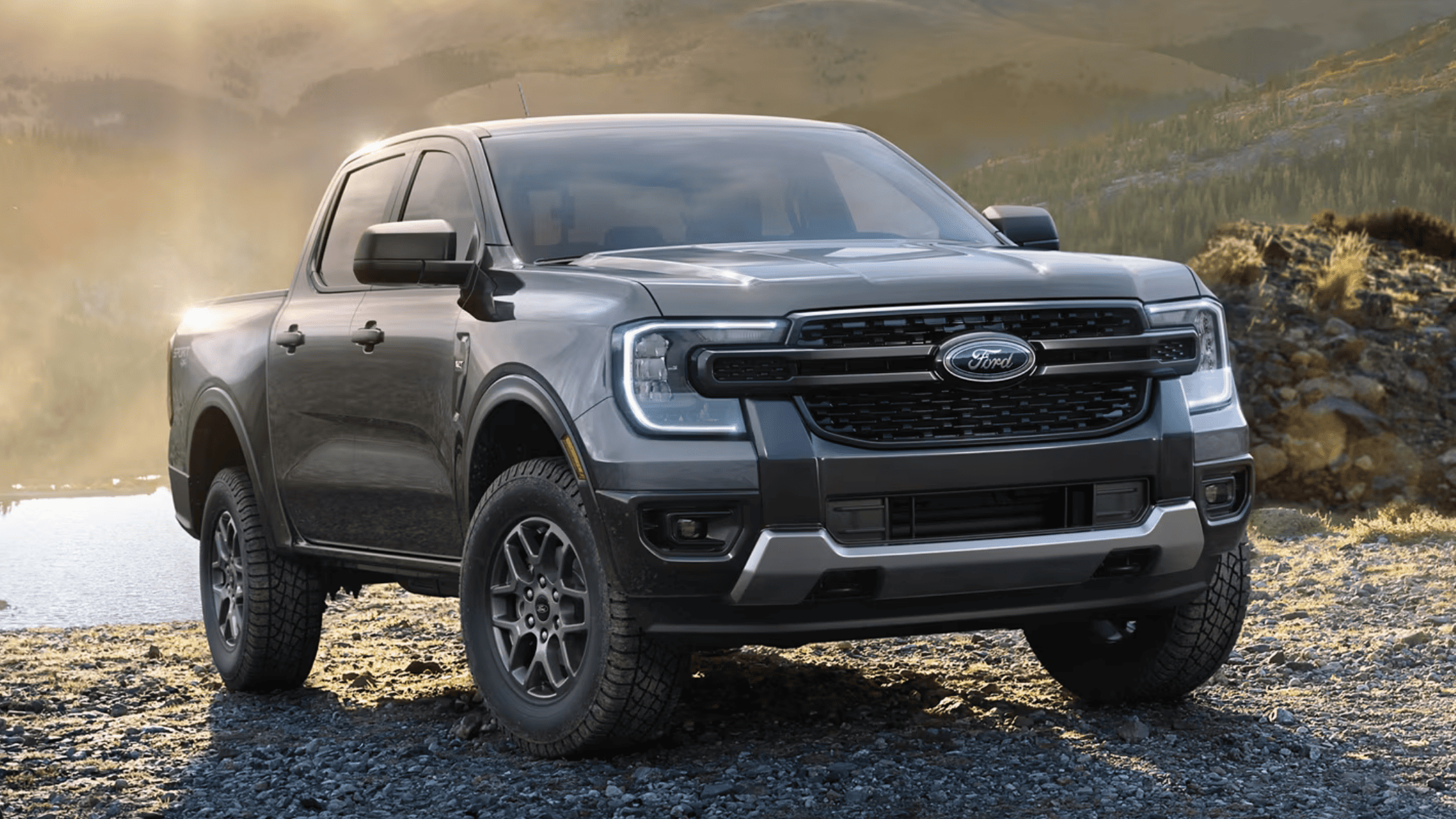 Front view of the 2025 Ford Ranger® parked on rocky terrain, highlighting its bold grille, LED headlights, and rugged off-road design.